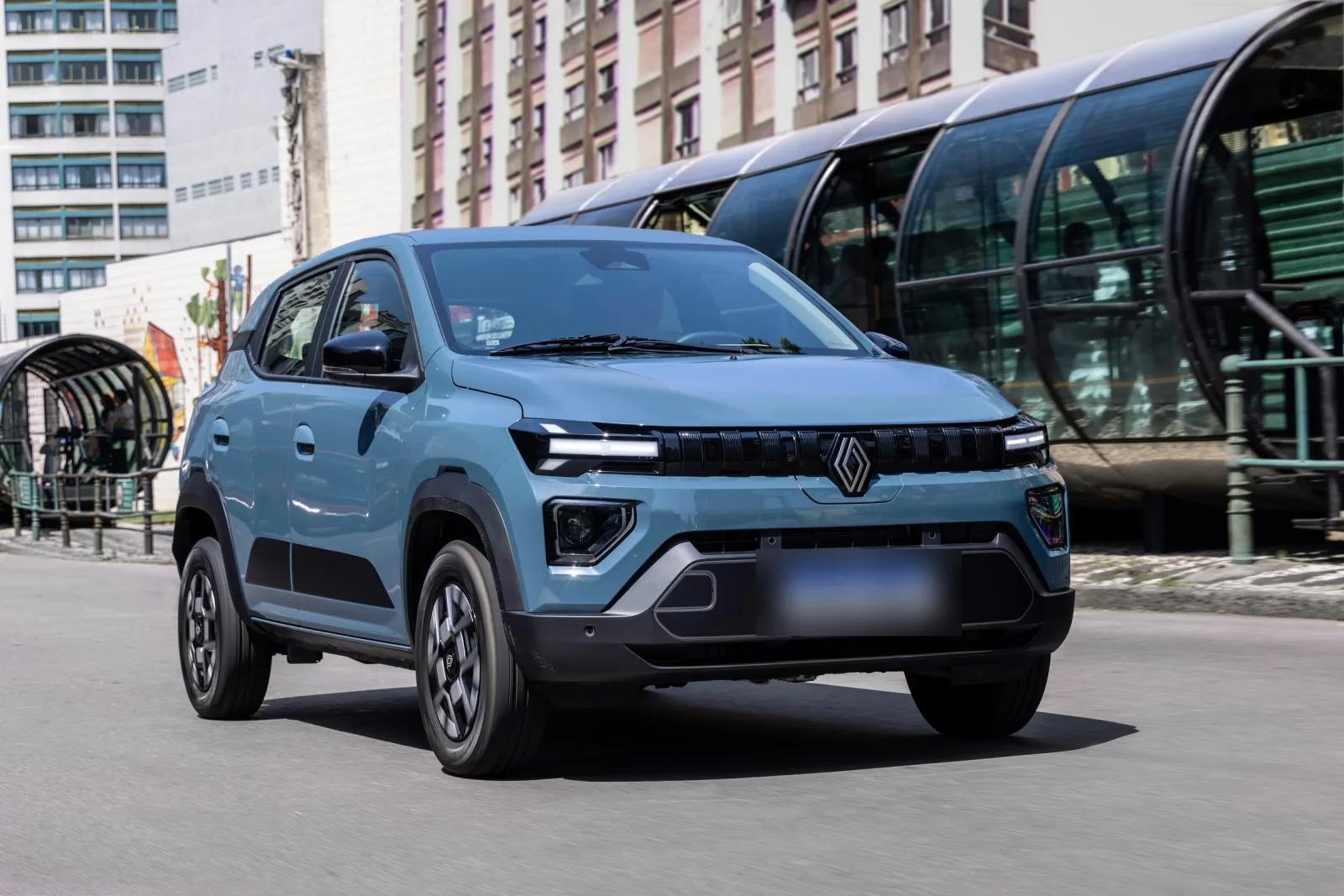 O Kwid E-Tech com o visual novo passa por uma estação-tubo de ônibus em Curitiba, na foto de lançamento de 2025